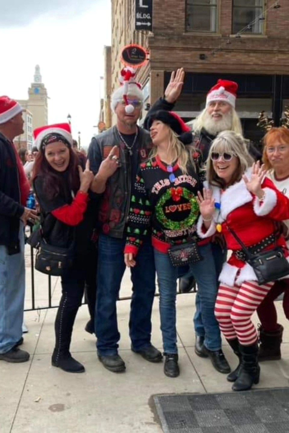 Group of attendees in festive Christmas outfits posing together outside during a holiday event.