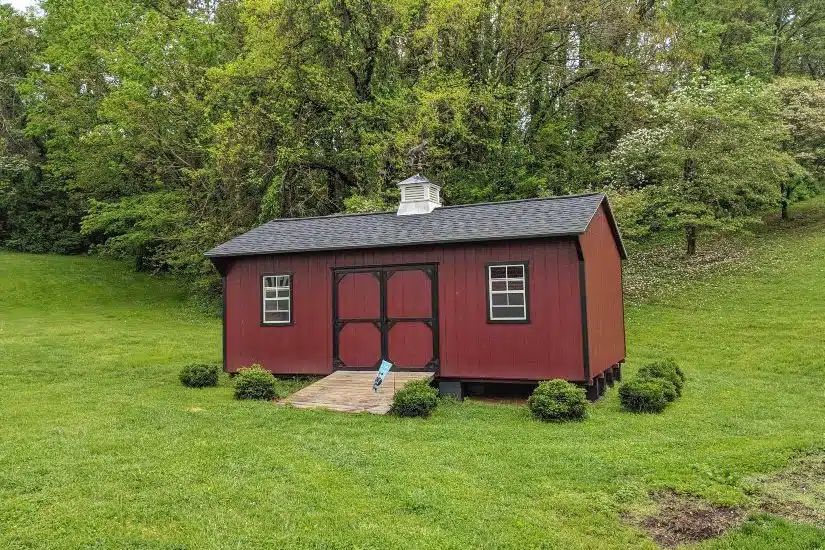 Red Quaker shed with cupola, black trim and wood ramp on an Elizabethton TN lawn