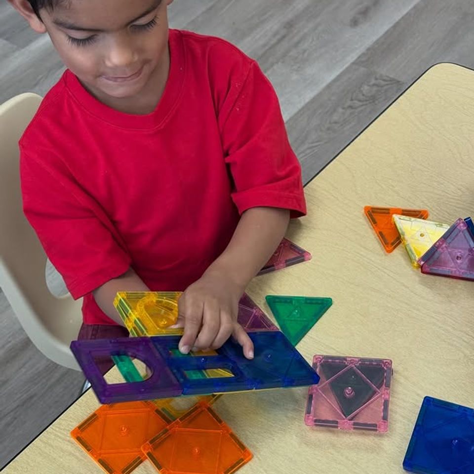 Boy building with colorful magnetic tiles at a classroom table during preschool learning time in Palmdale CA