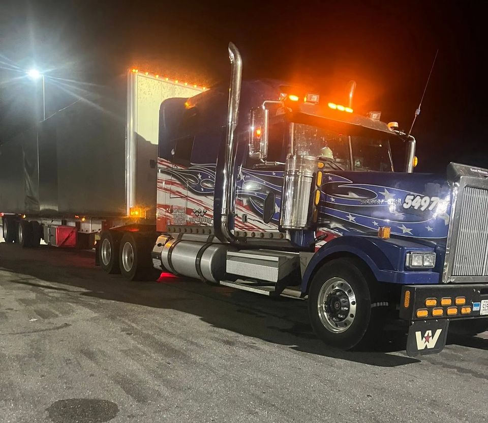 Blue Western Star semi-truck with American flag graphics at night roadside service in Arab Alabama