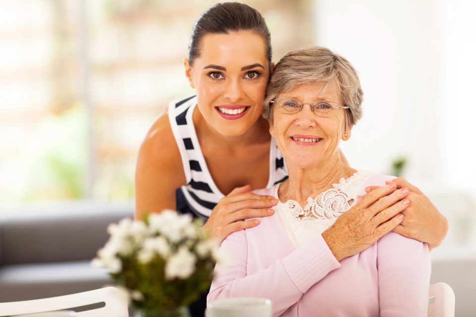 Caregiver embracing smiling senior woman during in home companion care on Long Island NY