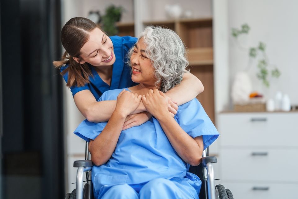 Caregiver and elder smiling and hugging on wheelchair in Houston, Texas