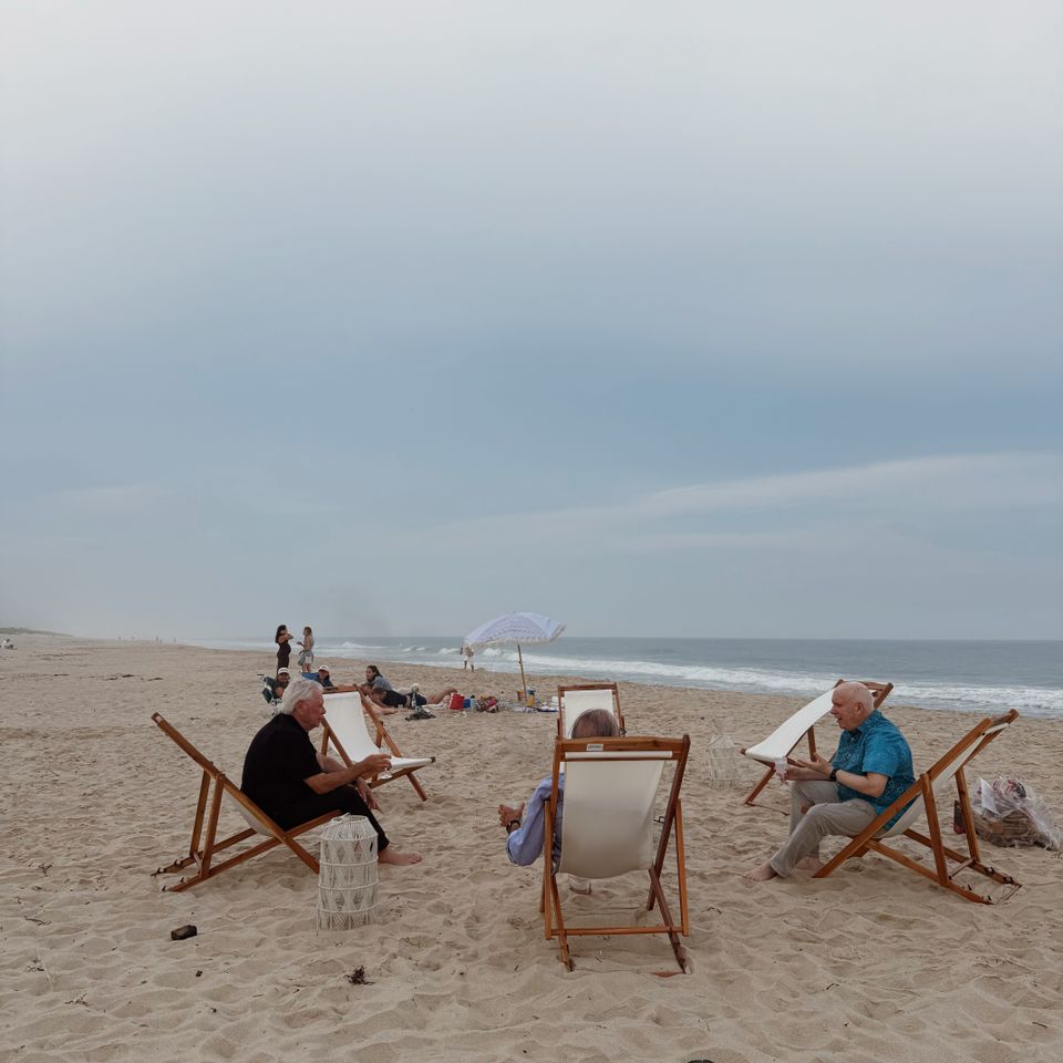 Guests relaxing in sling chairs around a beach fire setup on the shoreline in the Hamptons NY