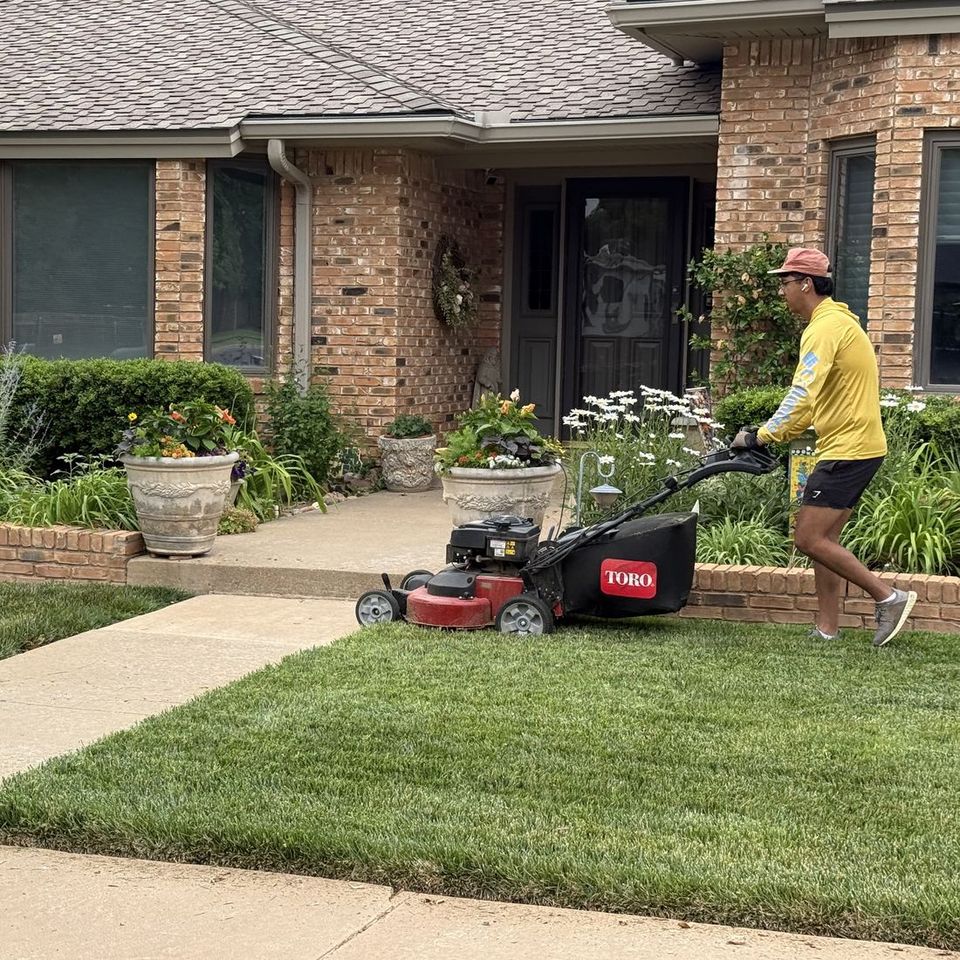 Mowin N Goin crew member mowing a brick home's front lawn in Lubbock