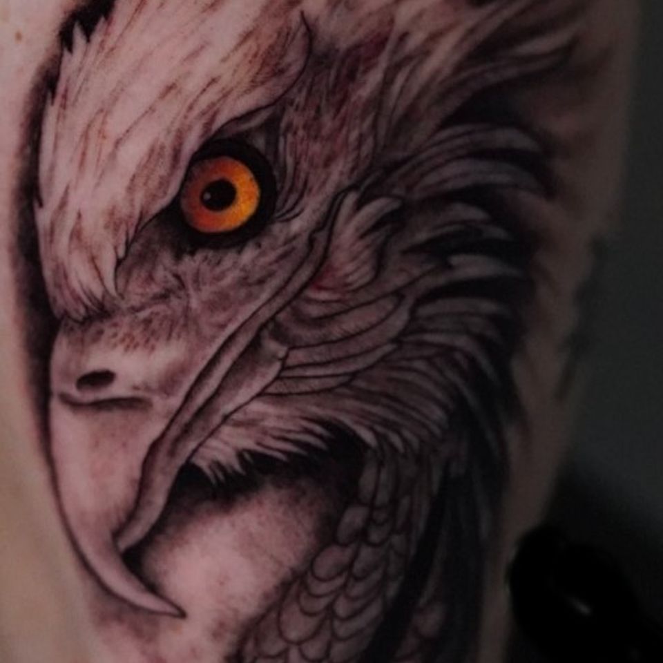 Image of a tattoo by Crazy Eagle that is a black and grey eagle with a golden eye created by Adrian Anderson