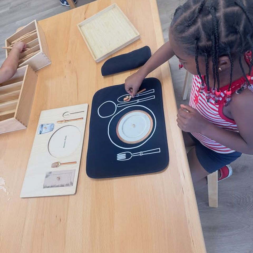 Preschool girl setting a place mat with utensils during Montessori practical life table setting work in Palmdale CA