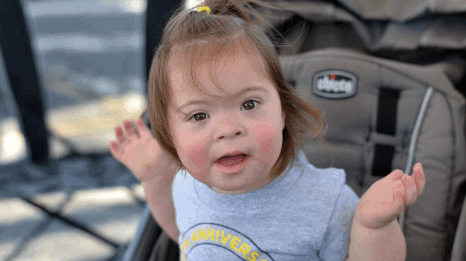 Smiling young child with Down syndrome at a Down Syndrome Association of the Valley community event.