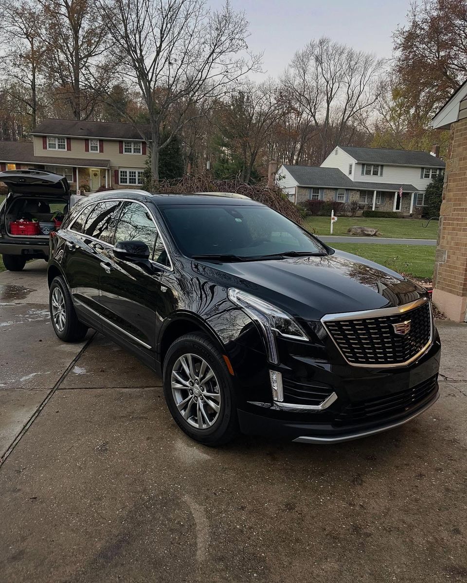 Glossy black Cadillac XT5 parked in a residential driveway after a mobile exterior detail near Wilmington