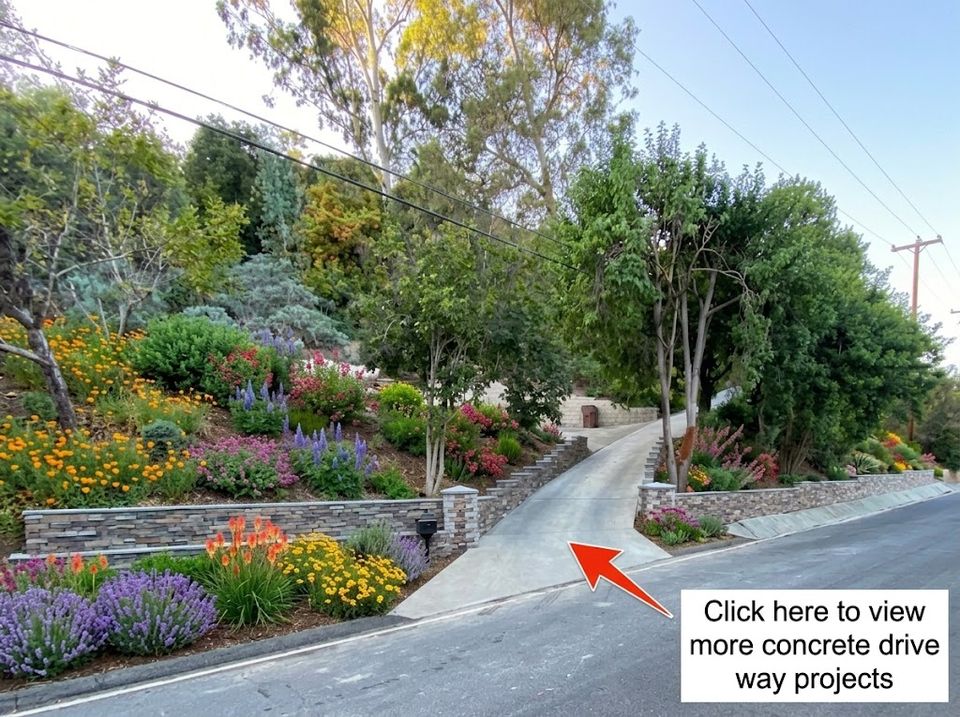 Residential concrete driveway installation with decorative landscaping and retaining wall features