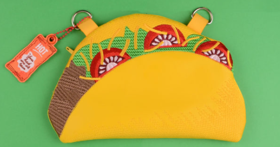 Custom embroidered taco-shaped zipper pouch with lettuce, tomatoes, cheese, and a hot sauce charm.