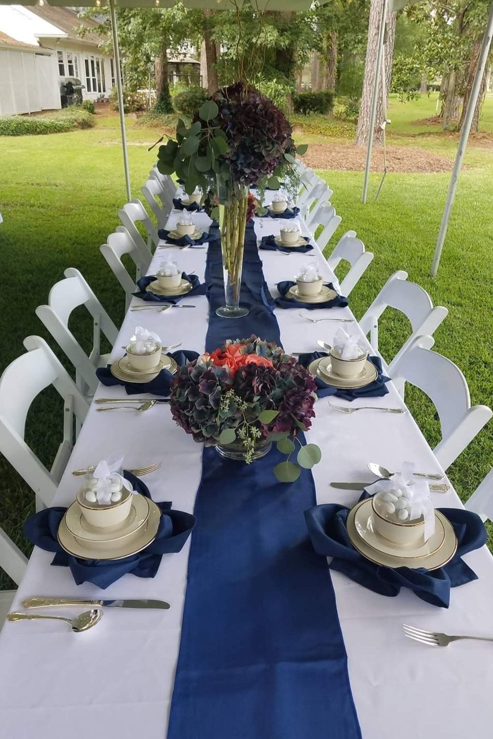 Outdoor reception table with elegant place settings, navy table runner, and floral centerpieces arranged by Carpe Diem Events