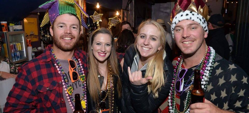 Guests celebrating at a Carpe Diem Events Mardi Gras balcony party wearing beads and festive costumes inside the Bourbon Street venue.