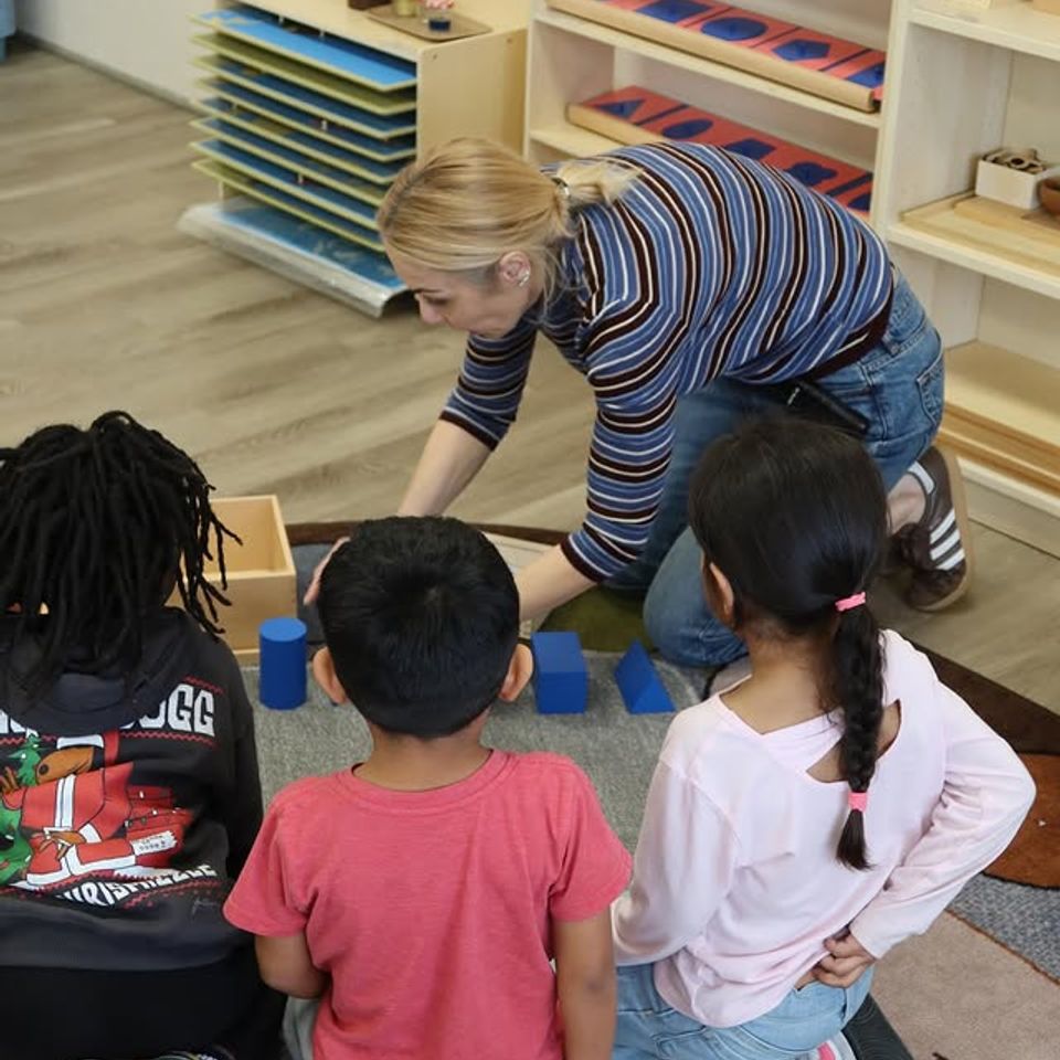 Teacher presenting Montessori sensorial cube materials to a small group of preschoolers in Palmdale CA