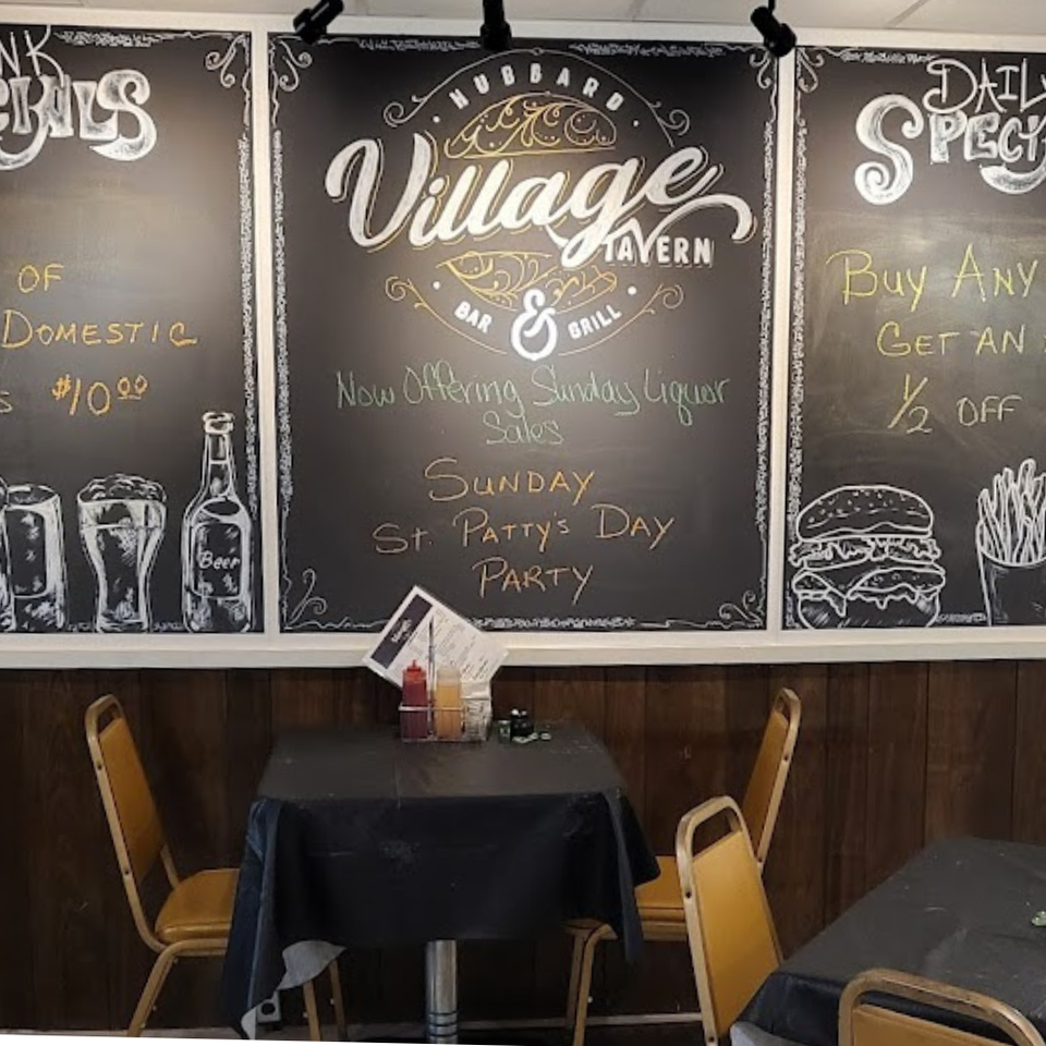 Chalkboard wall at Village Tavern displaying drink and food specials above dining tables
