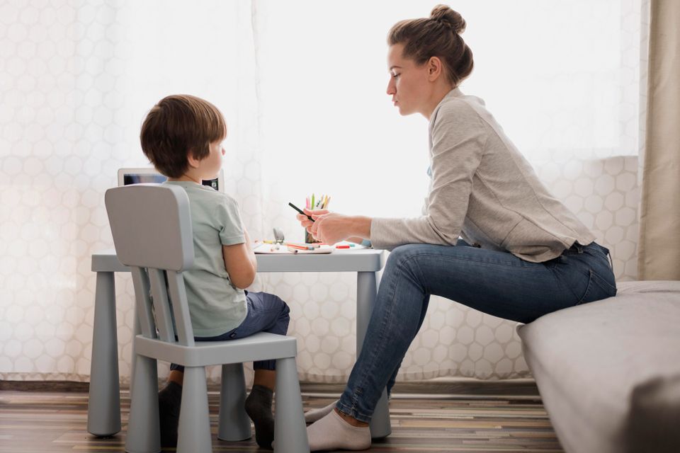 Side view woman tutoring child home (1)
