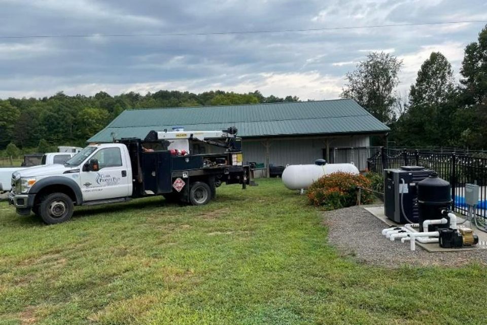 Propane installation service truck parked at a rural home, near a newly installed propane tank and generator, showcasing expert residential propane delivery and setup.