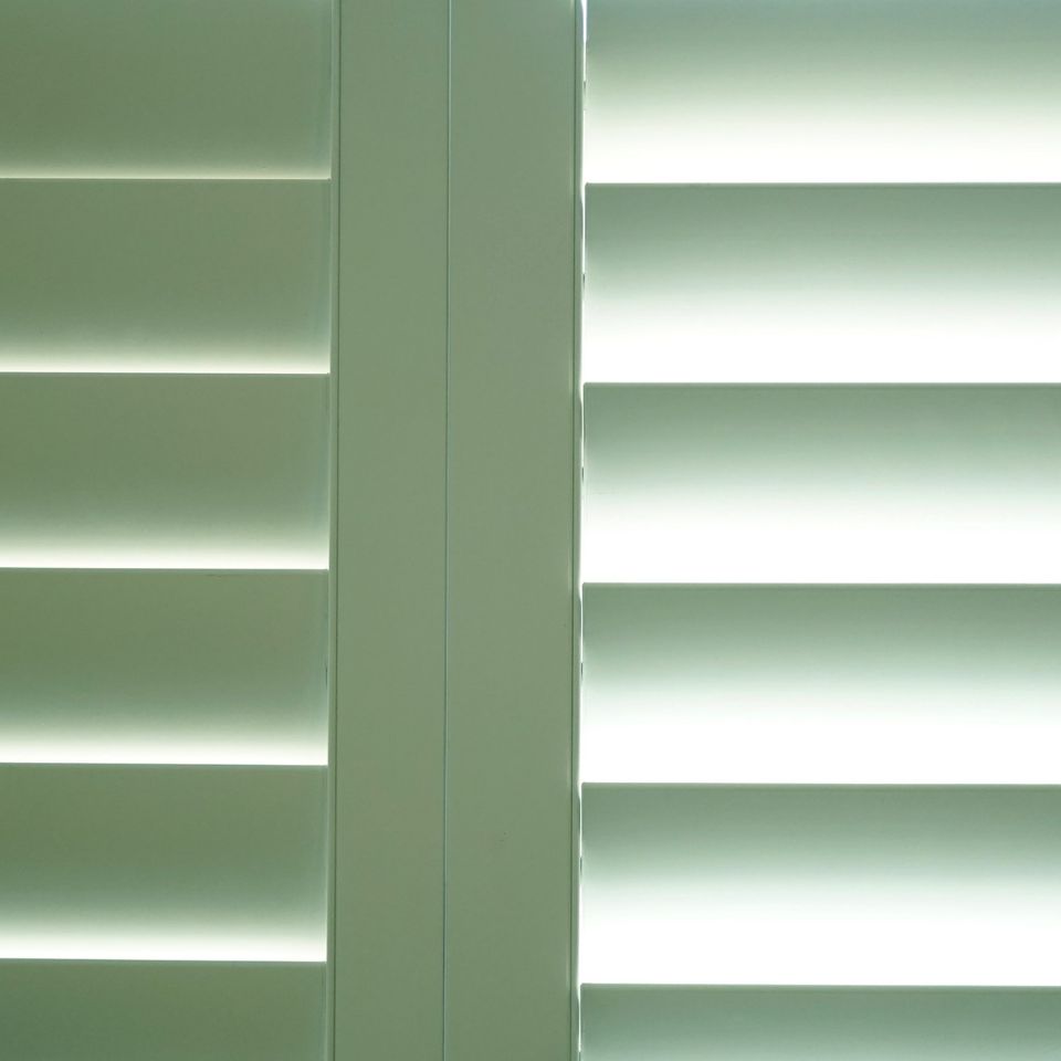 Interior plantation shutters installed on tall windows in a bright living room