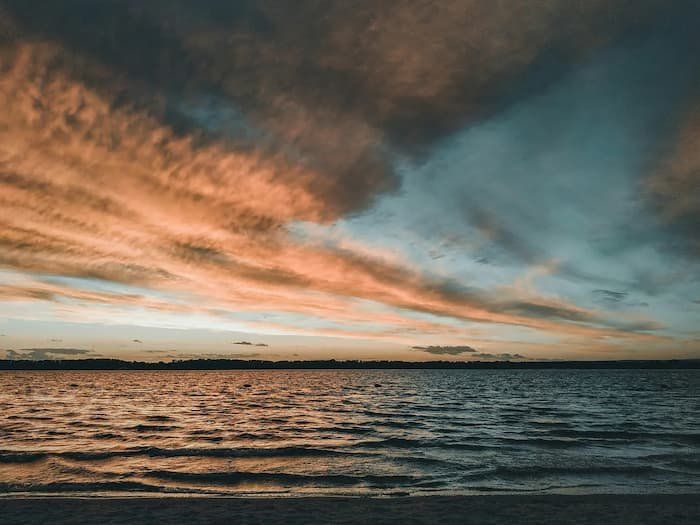 Sunrise over a body of water with oranges and blues displayed 