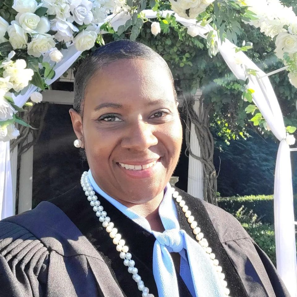 Wedding officiant Dee Dee smiling under floral arch after ceremony in Queens New York