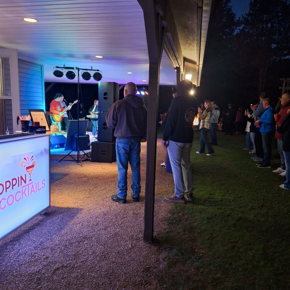 Guests watching live band with a full bar setup at a private outdoor event