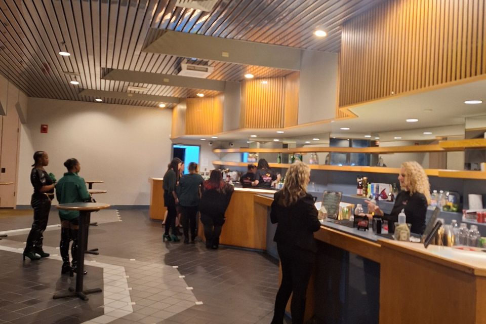 Bartenders serving drinks at a large indoor bar setup during a formal event