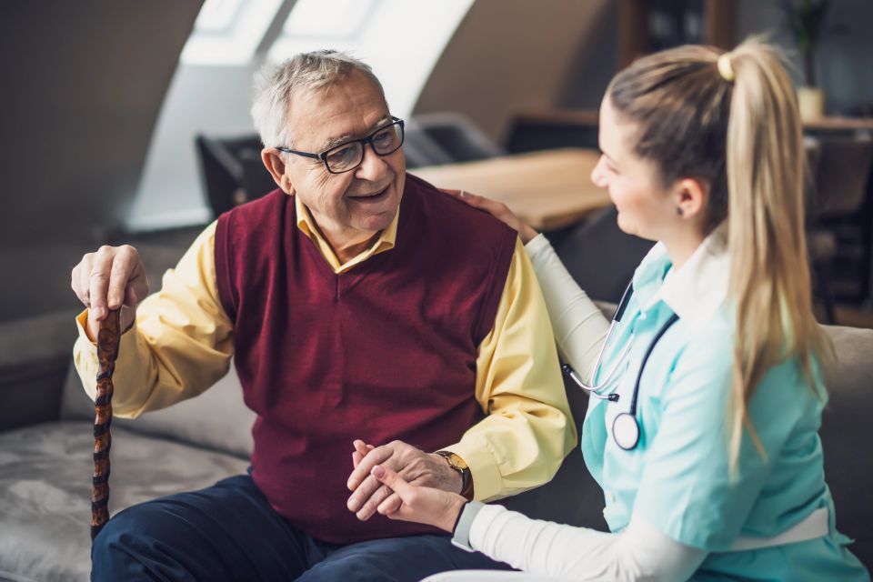 Nurse home caregiver is assisting old man at his home