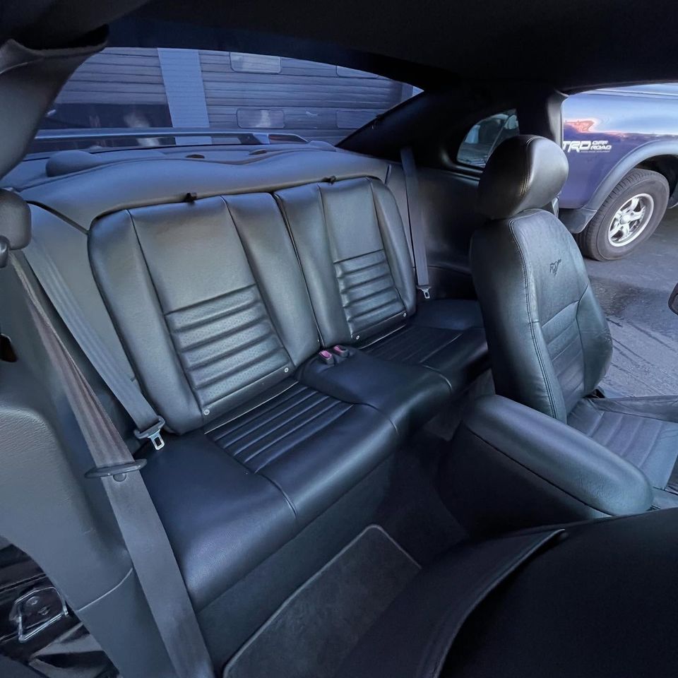 Conditioned black leather rear bench seat in a Ford Mustang after interior cleaning