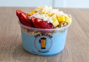 Super Blue bowl with blue spirulina base, strawberries, mango, coconut, granola, and honey drizzle.