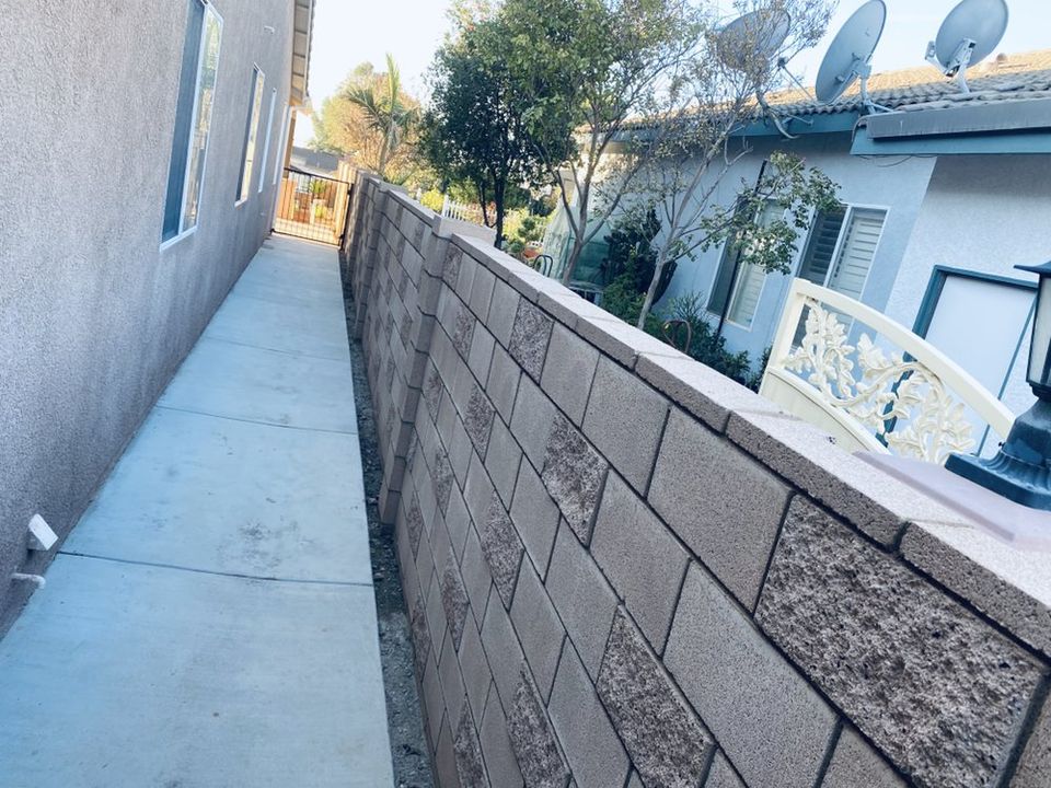 Concrete block wall alongside residential side yard walkway providing privacy and property separation