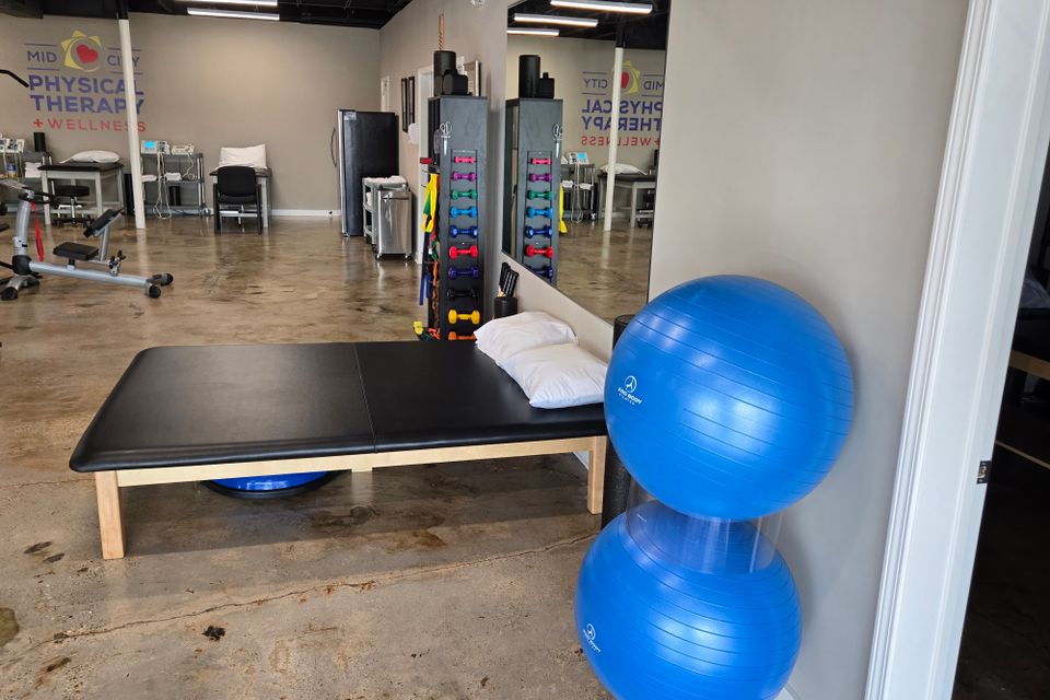 Padded treatment table with pillows and two physioballs in a therapy room at Mid-City Physical Therapy's Metairie clinic