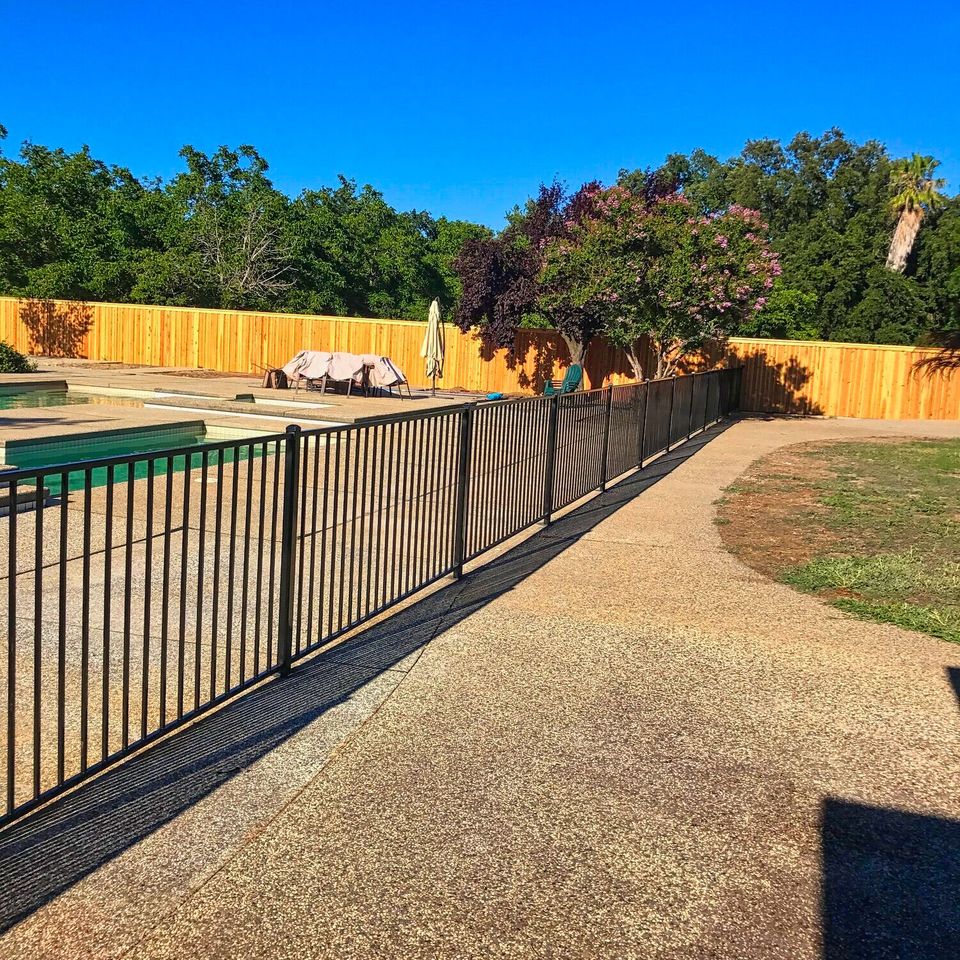 Black metal pool safety fence installed around residential swimming pool
