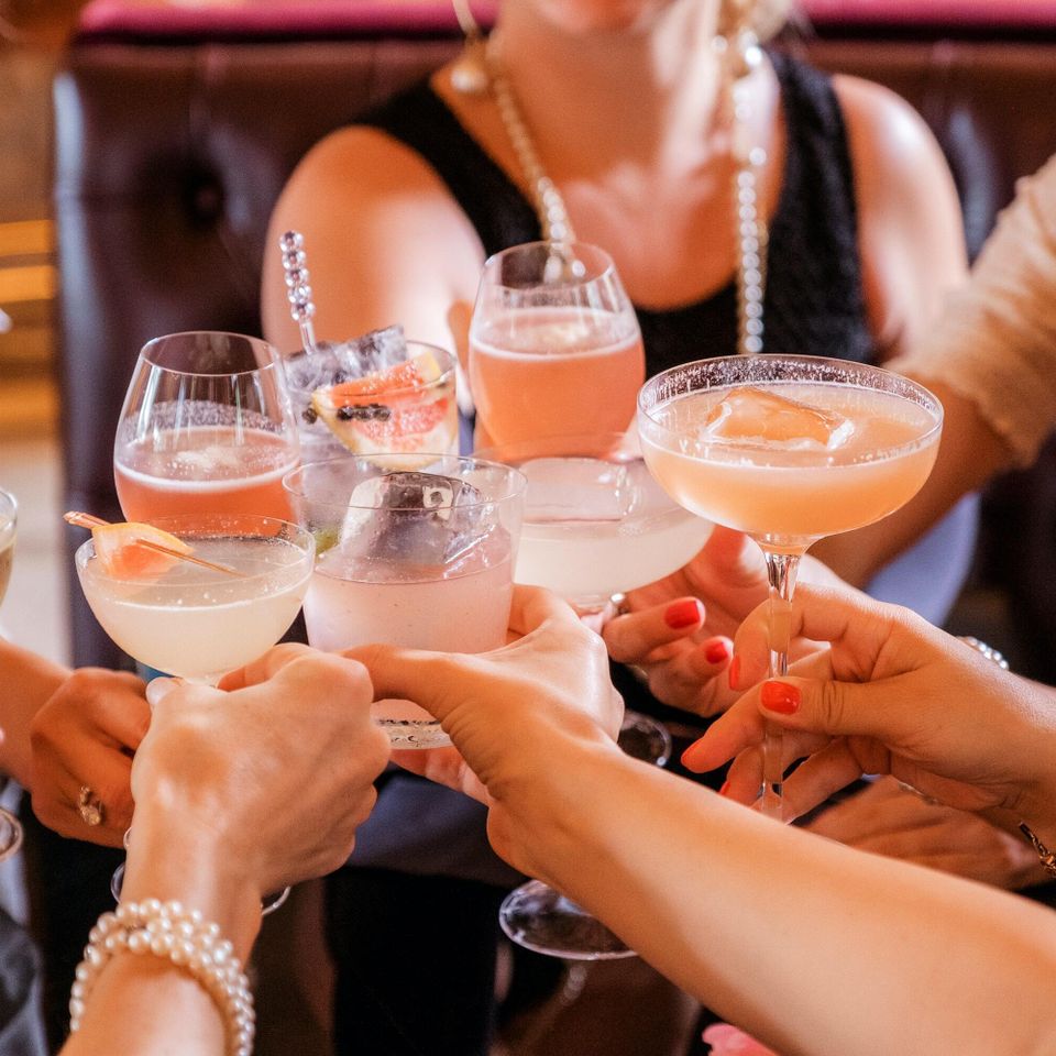 Several adults toasting with different handcrafted beverage glasses