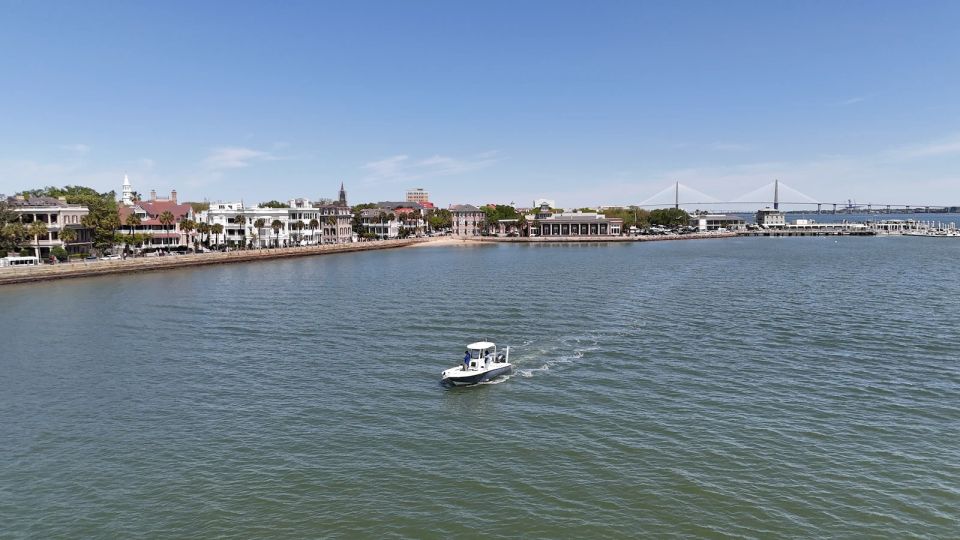 Charleston boat cruising through the harbor with historic homes and Ravenel Bridge in the background