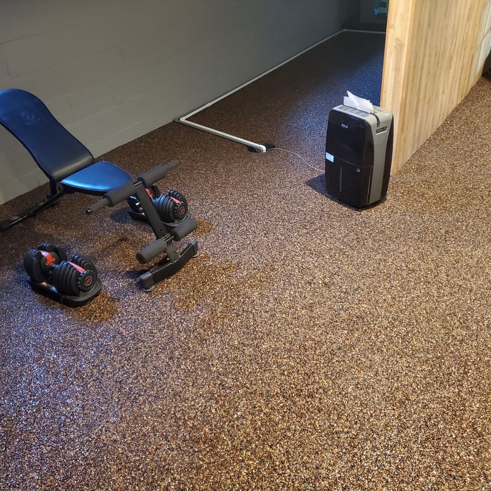 Home gym featuring a decorative flake epoxy floor with workout bench and adjustable dumbbells.