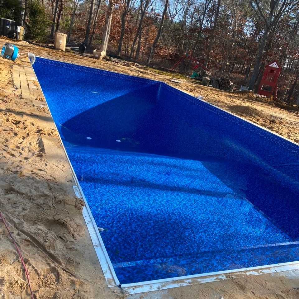 New blue vinyl liner set in a rectangular inground pool before backfill and coping on Long Island