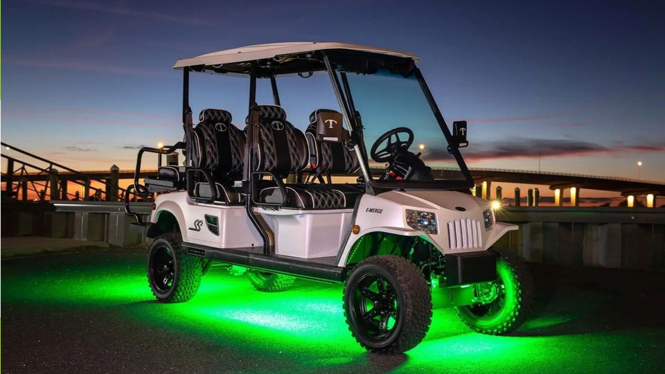 White customized golf cart with undercarriage lighting in Madisonville, LA at sunset near a bridge