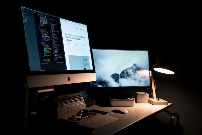 Two screens at a work desk 