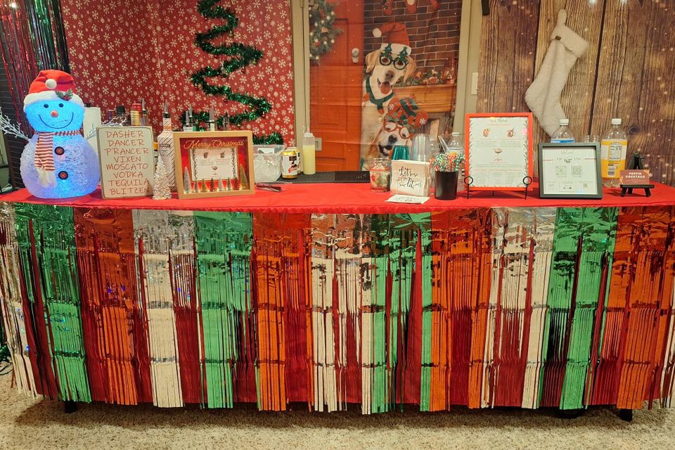 Festive bar setup with Christmas decorations, menu, and drink supplies on a table