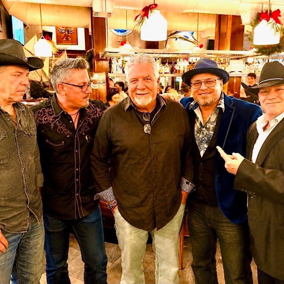 Five members of Roadside band posing together inside a restaurant before a private party gig