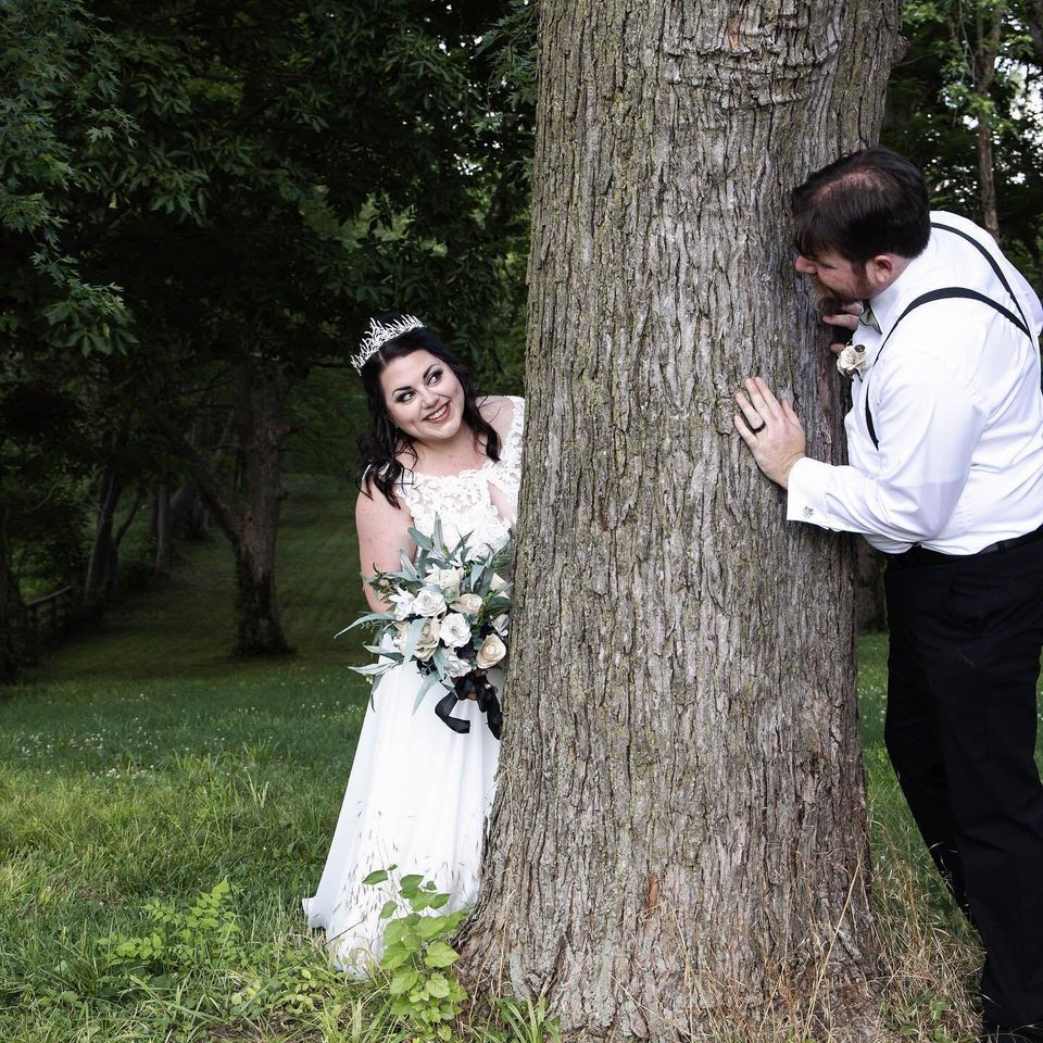 Bride and groom playing hide and seek behind a tree