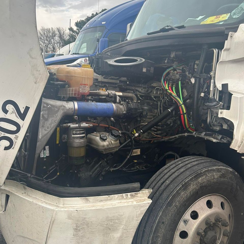 Detroit diesel engine bay exposed under raised hood during semi-truck repair in Arab Alabama