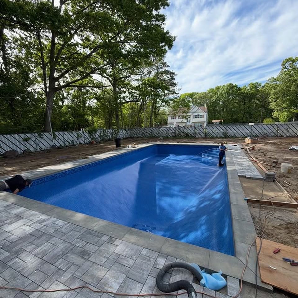Crew filling a rectangular inground pool with a new liner and paver deck in Long Island NY