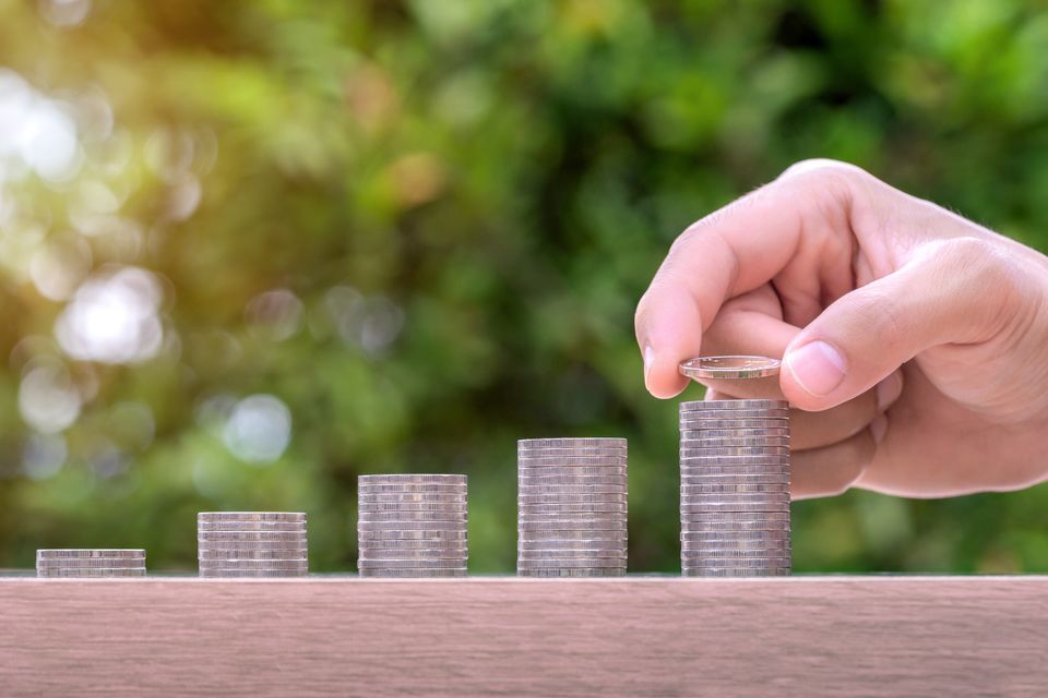 Hand holding coin stack money wood table pension fund concept