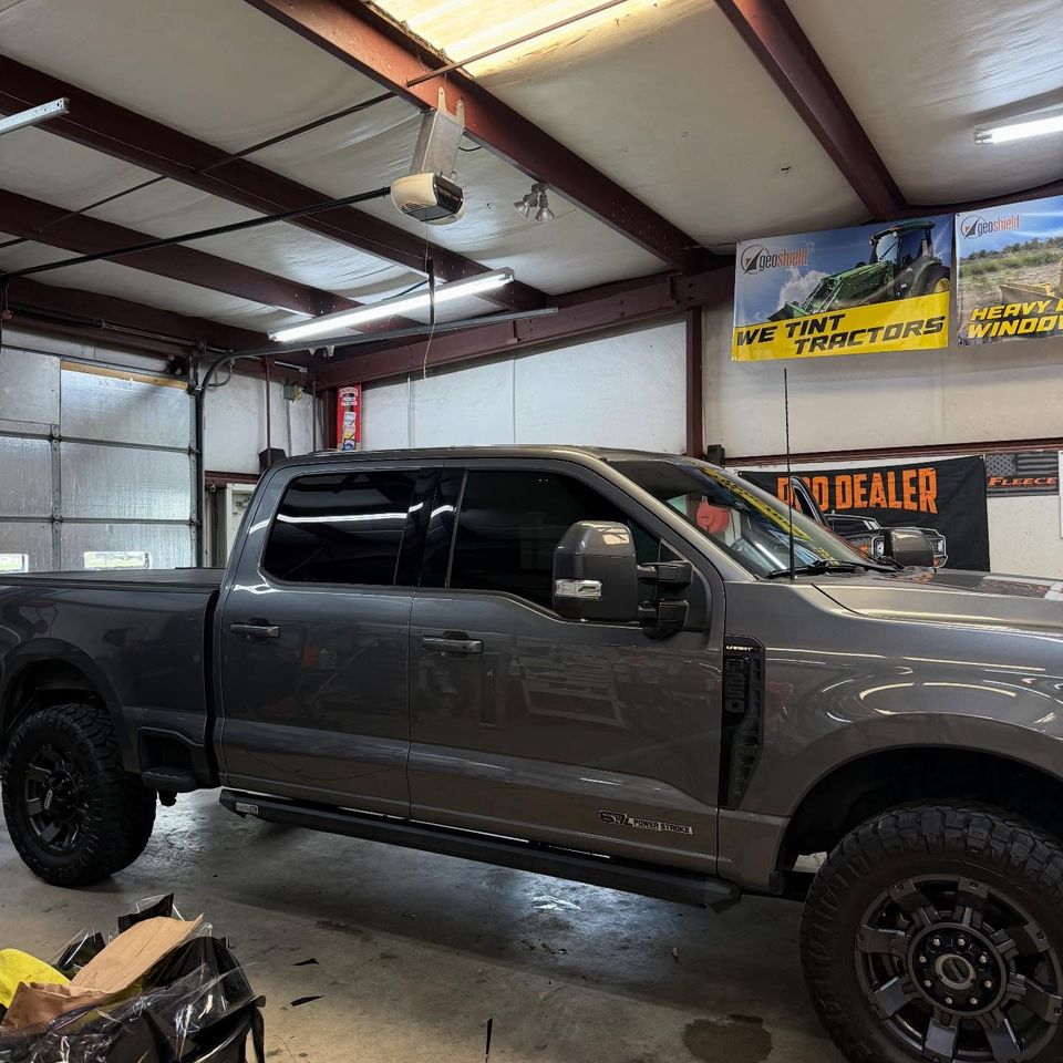 Gray Ford Super Duty crew cab with dark tinted windows inside the window tinting bay