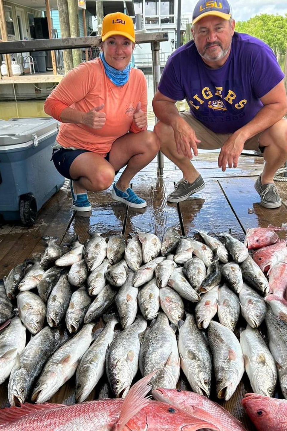Two happy customers with several dozen fish in front of them after a fishing charter with Carpe DIem events