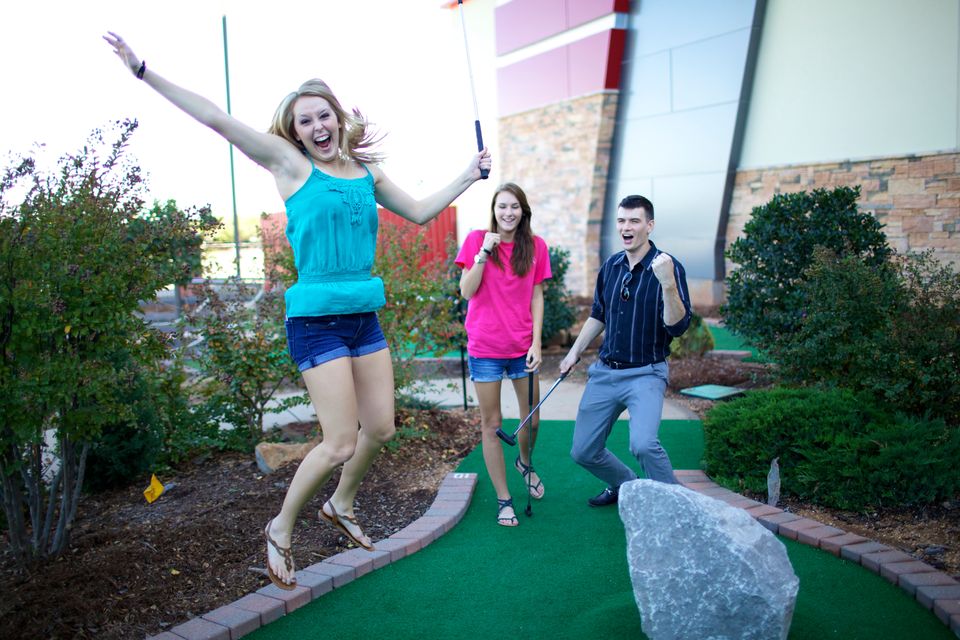 Three people celebrating while playing miniature golf at Putt Putt Hey Day