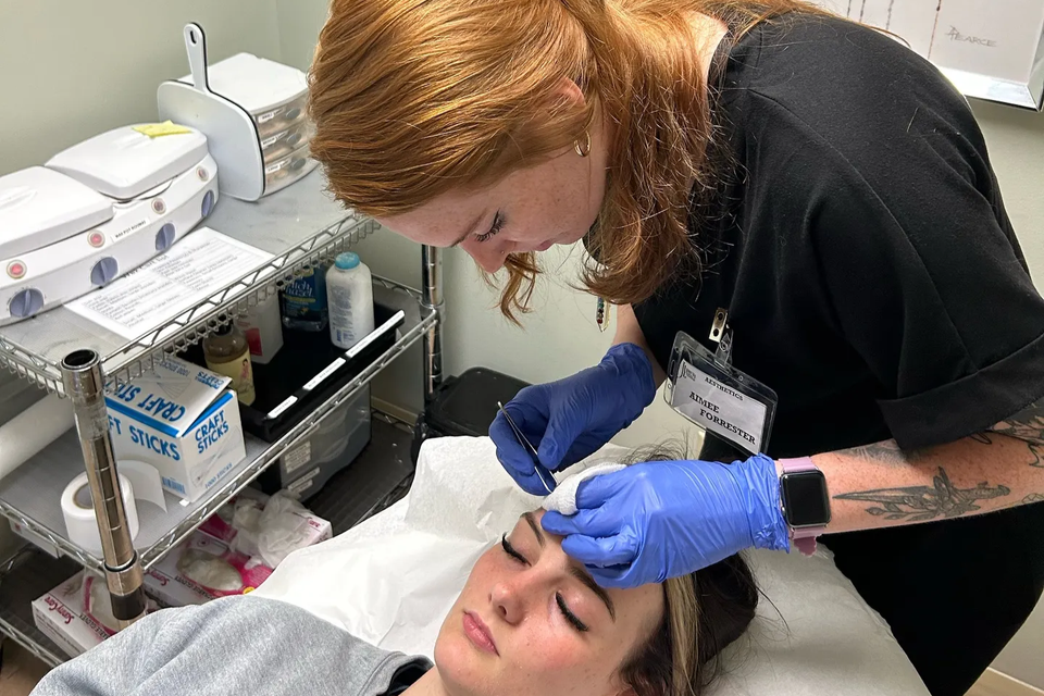 Esthetician student performing facial treatment in training room