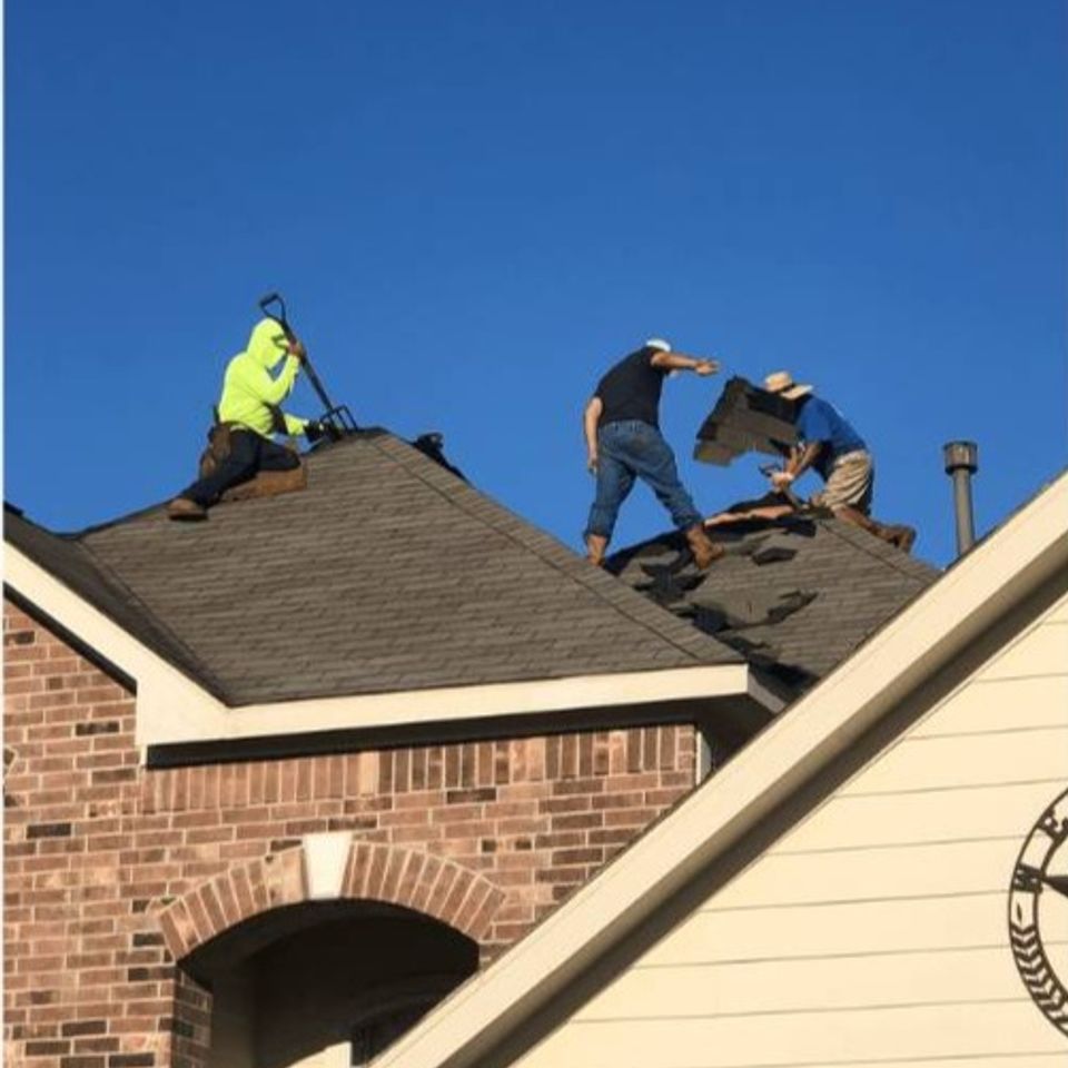 Roofing crew installing new shingles on residential roof in the North Houston area