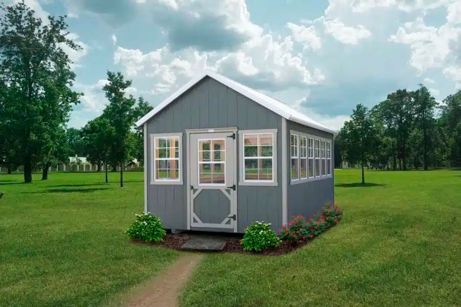 Gray gardener greenhouse shed with white trim and glass windows on a Knoxville TN lawn