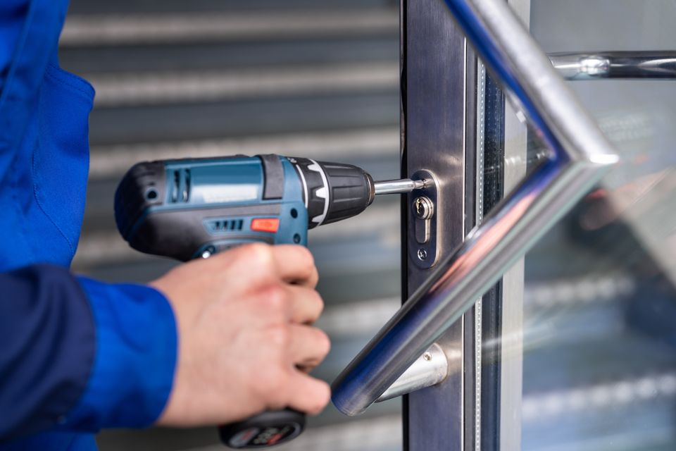 Professional locksmith using an automatic screwdriver to change a commercial lock